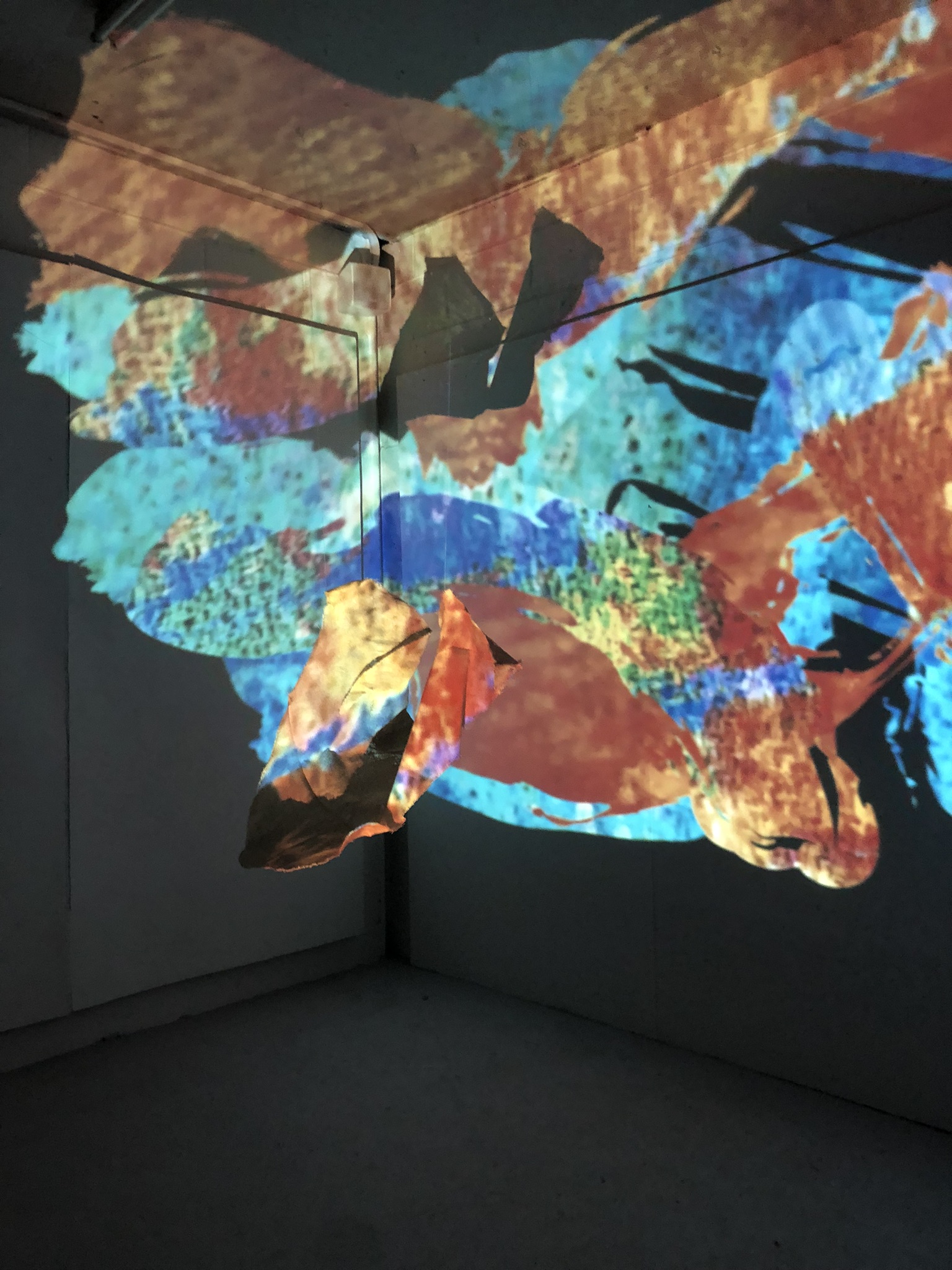 An image of an array of colourful digitized brushstrokes which "paint" the surface of a fabric sculpture which hangs in the centre of the space