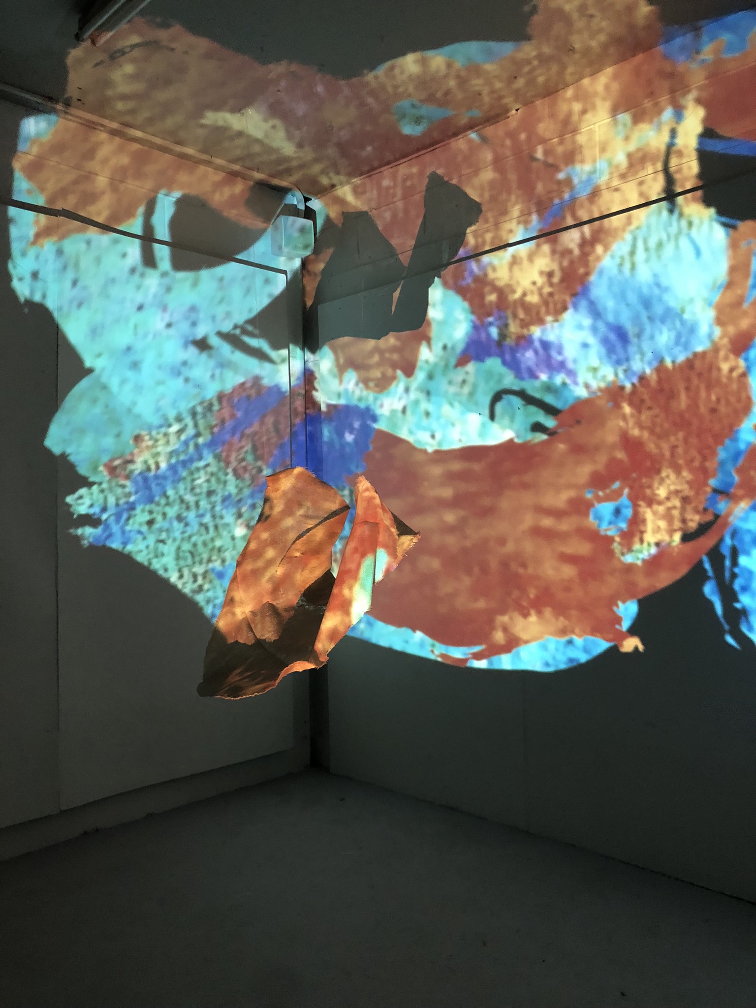 An image of an array of colourful digitized brushstrokes which "paint" the surface of a fabric sculpture which hangs in the centre of the space