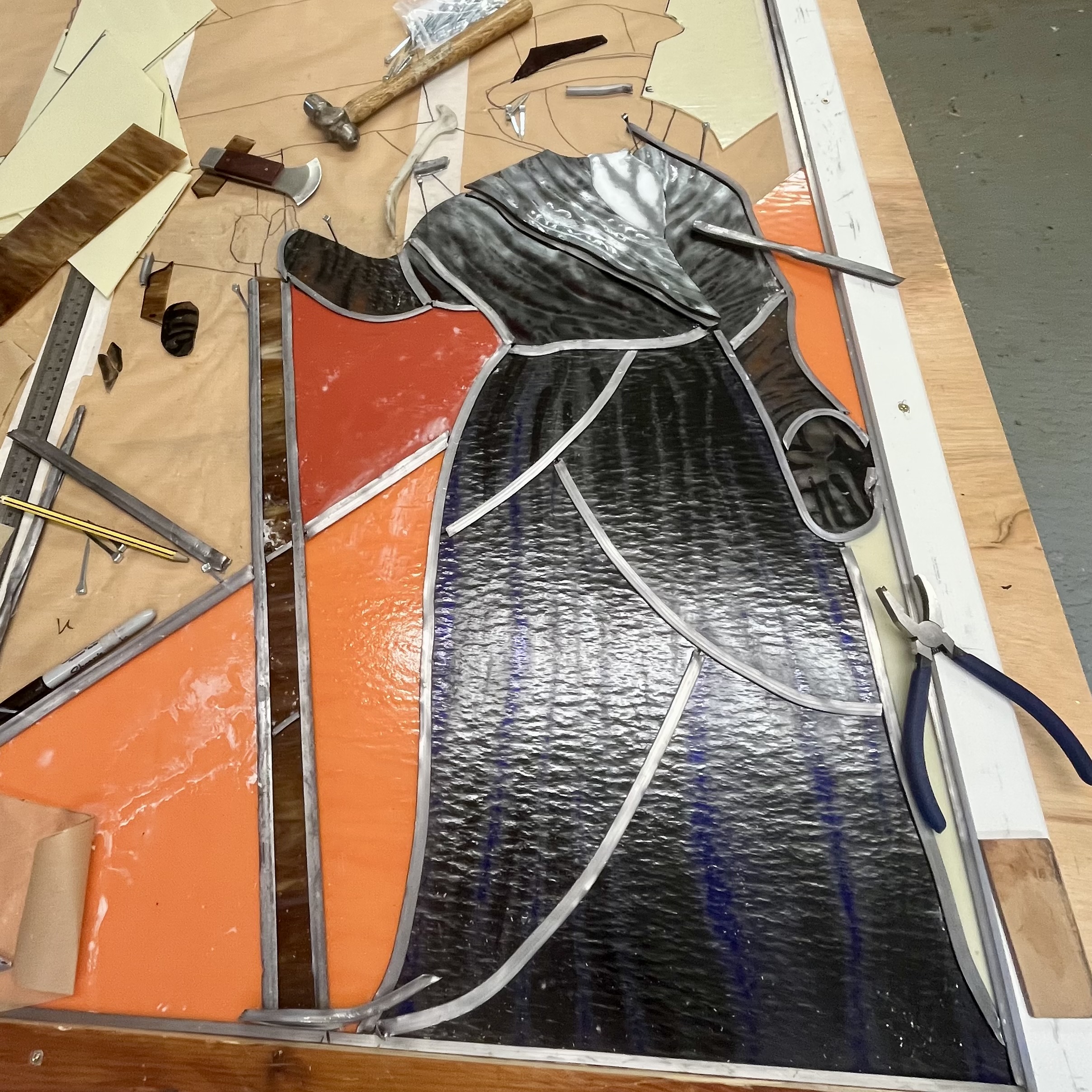 Photo showing the process of leading up a stained glass panel.