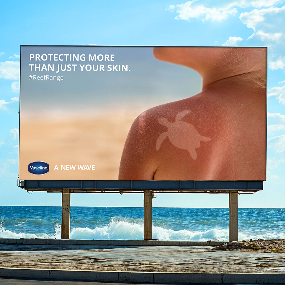 Billboard by the sea displaying a Vaseline ad with a sun-tanned shoulder showing a turtle shape, captioned ‘Protecting more than just your skin’ promoting reef-safe skincare.